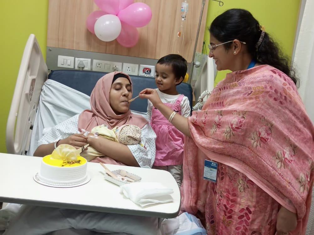 Dr. Asna Zehra Naqvi celebrating a postpartum cake ceremony with a mother, newborn and child in Lucknow